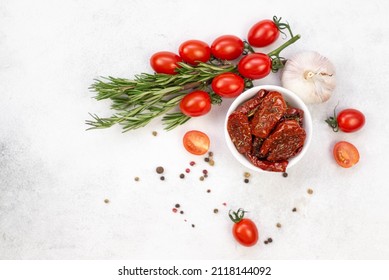 Sun dried tomatoes with fresh herbs, spices, tomatoes and garlik. Grey background. Top view.