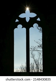 Sun falling through the Gothic window of a castle ruin