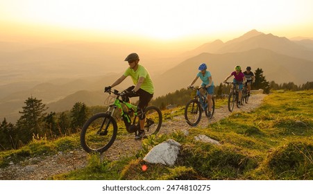 SUN FLARE: Cheerful Caucasian tourists ride electric bicycles up a mountain trail at sunset. A group of cross country bicycle riders traveling across the scenic mountains of Slovenia at golden hour. - Powered by Shutterstock