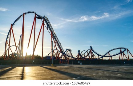 SUN FLARE Gorgeous sunset illuminates an empty roller coaster ride in a big amusement park in Los Angeles. Golden summer morning sunbeams shine on an empty thrill ride on the famous Santa Monica Pier. - Powered by Shutterstock