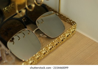 Sun glasses' s women in golden tray on wooden built in. Close up eyeglasses beach with aluminum frame for sun protection. Woman accessories for fashion and beauty. Luxury blinkers