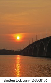 a sun goes down at the end of bridge