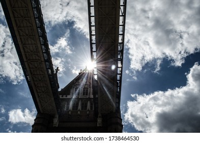 Sun going across London bridge's structure in a cloudy day