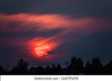 Sun Going Down Amid Clouds Beyond Silhouettes Of Trees, Power Line, And Lampposts Above A Suburban Parking Lot In Summer, Northern Illinois, USA, For Meteorological, Environmental, And Temporal Themes