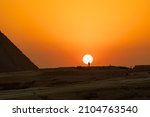 The sun is going down behind the pyramid and a silhouette of a man standing on the hill, Giza, Egypt