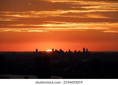 As the sun gracefully sets over the sprawling city skyline, the colors of amber and orange fill the sky with a breathtaking afterglow