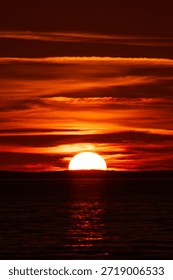A sun, half set,  on a sunset sky illuminating the 