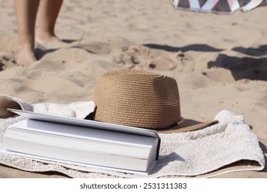 a sun hat with a book to read in the beach sand - Powered by Shutterstock