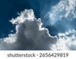 Sun hidden behind a dramatic cloud with backlit edges and sunbeams
