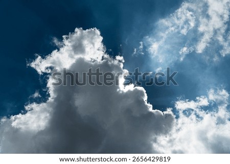 Sun hidden behind a dramatic cloud with backlit edges and sunbeams