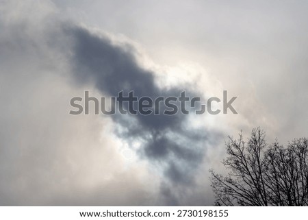 The sun hiding behind a grey cloud