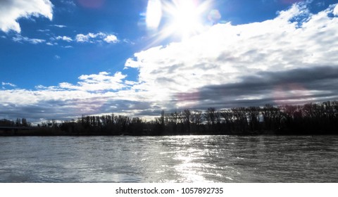 Sun Light shining through cloudy sky, shimmering reflection in rippling river waters 