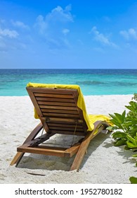 Liegestuhl mit gelbem Handtuch am tropischen Strand am Meer, Draufsicht