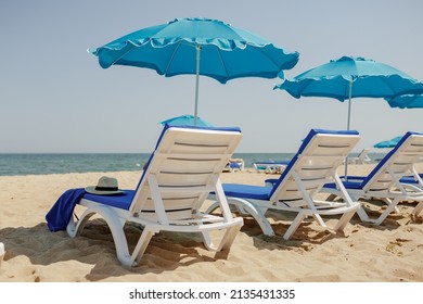 sun loungers on the sand near the sea and umbrellas