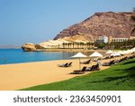 Sun loungers and umbrellas under palm trees on gorgeous beach on a sunny summer day. Omani Beach at the Barr Al Jissah Resort in Oman