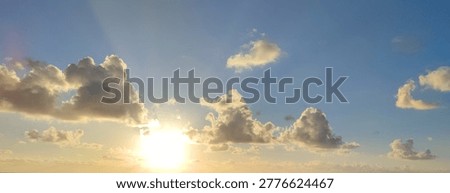 sun low in sky with clouds over horizon