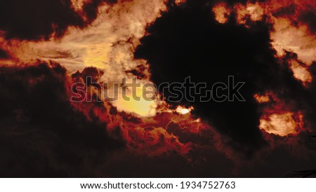 sun obstructed by a large thick cloud during twilight, with the surrounding clouds stirred by the winds and tinged with orange and red.