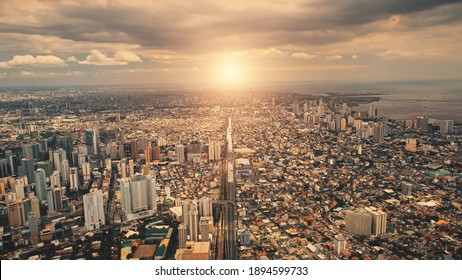 Sun over city roofs of skyscrapers buildings aerial. Urban traffic road at streets of downtown. Philipines capital cityscape at summer sunlight. Filipino town cinematic soft light drone shot - Shutterstock ID 1894599733