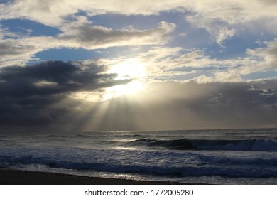 Sun peaking through the clouds above the ocean.