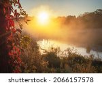 The sun peaks over the distant tree line as steam and fog collect in the marshy river basin in Waukesha County, Wisconsin on an autumn morning.