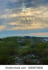 Sun Peeking Through Clouds Over Beach