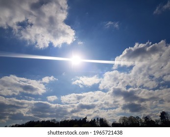 The sun peeks through the clouds. Cloudy blue sky. Bright sun in a blue sky