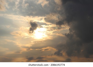 The sun peeks through the clouds of a soft blue color