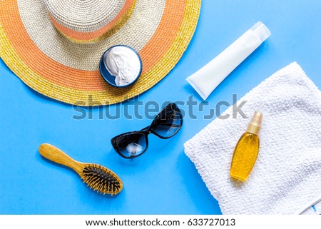 Sun protection composition with glasses and cream on blue background top view