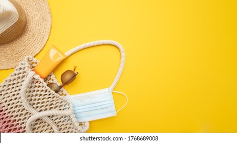 Sun protection object in macrame bag. Straw beach hat, sunglasses, spf cream, surgical mask on bright yellow background. Beach accessory. Summer Travel Vacation in coronavirus. New normal.  - Powered by Shutterstock