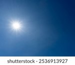 The sun radiates intensely in a vast, cloudless blue sky without any foreground elements.