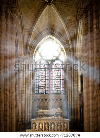 sun rays beaming through the old stained glass window of saint denis cathedral and lighting interior with tomb. Paris, France, Europe.
