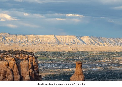 Sun rays break through storm clouds above the Book Cliffs and Independence Monument near Grand Junction, Colorado.
