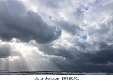 Sun rays breaking through the clouds of a dramatic stormy sky over the Mediterranean Sea with foamy waves. Israel