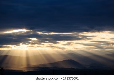 sun rays breaking through the clouds over a mountain landscape