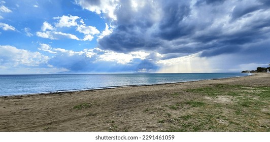 sun rays breaking through the clouds on the sea sandy beach. beauty in nature. dark storm clouds cover the sky, the rays of the sun form beautiful light streaks