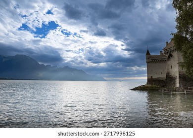 Sun Rays Breaking Through Clouds Over Mountain Lake Near Medieval Castle