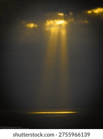 Sun rays breaking through clouds over ocean with golden light reflection