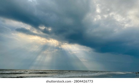Sun rays breaking through clouds over ocean, crepuscular rays. clouds air scenery sun light blue sky. Dramatic sunset. Beautiful landscape with golden sun lights penetrated through dark clouds during sunset. Dramatic Sun Rays Breaking Through Clouds Over the Sea.