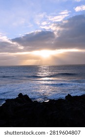 Sun Rays Breaking Through Clouds Over Ocean with Rocky Coastline