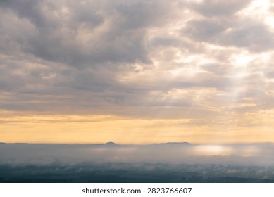 Sun rays breaking through clouds over misty landscape at Tiger Cave Temple, Krabi, Thailand