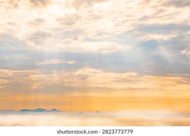 Sun rays breaking through clouds over misty landscape at Tiger Cave Temple, Krabi, Thailand