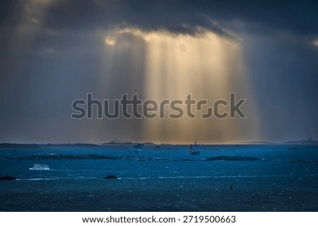 Sun rays breaking through clouds over ships at sea