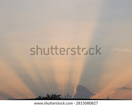 Sun rays breaking through clouds on a dramatic sky during sunset. Spectacular crepuscular rays shining over dark horizon.