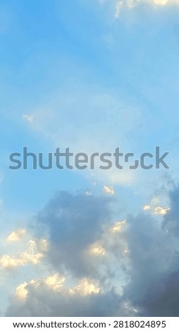 Sun rays breaking through clouds in the blue afternoon sky with golden sunlight