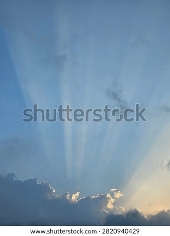 Sun rays breaking through clouds in the blue sky, beautiful crepuscular rays landscape background.