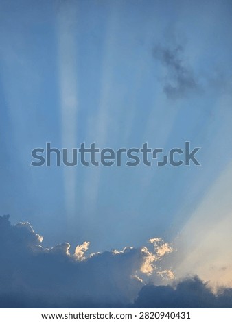 Sun rays breaking through clouds in the blue sky, beautiful crepuscular rays landscape background.
