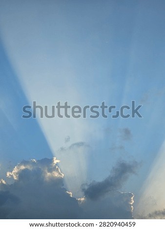 Sun rays breaking through clouds in the blue sky, beautiful crepuscular rays landscape background.