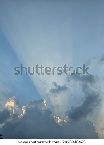 Sun rays breaking through clouds in the blue sky, beautiful crepuscular rays landscape background.