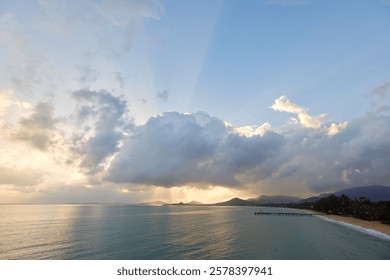 
Sun Rays Breaking Through Dramatic Clouds Over a Calm Sea and Hills