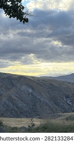 Sun Rays Breaking Through Dramatic Clouds Over Mountain Landscape